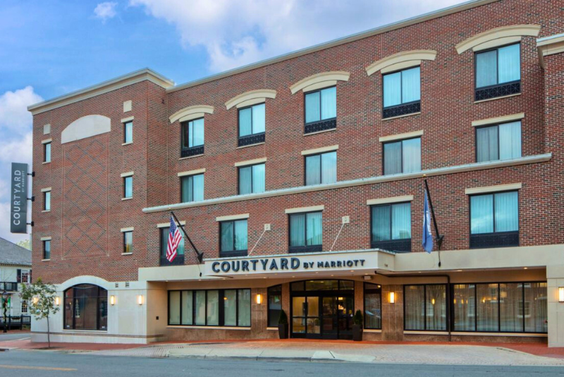 Exterior view of the Courtyard by Marriott hotel. It is a brick building, with multiple levels and flags outside.