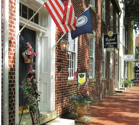 Photograph of the front of the Richard Johnston Inn with a American Flag and Virginia State flag hanging on the front door frame