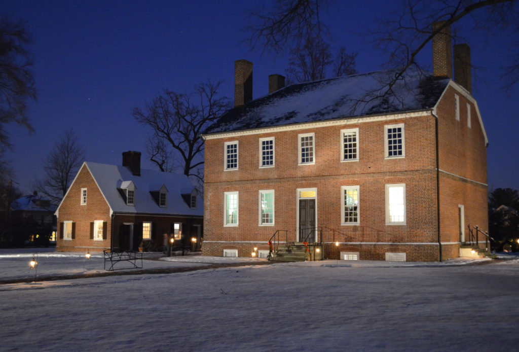 Historic Kenmore at night with snow on the ground and candles lit in the windows