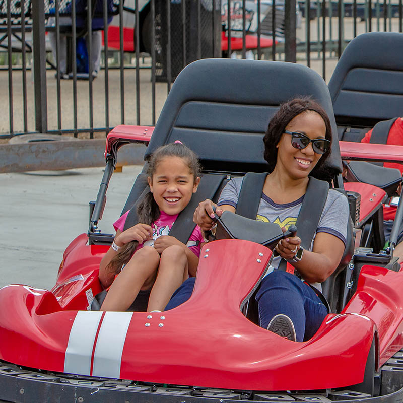 Mother and daughter having fun driving go-carts