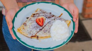 person holding a plate with a crepe