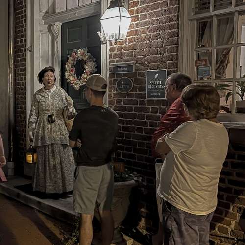 Tour guide dressing in 19th century dress giving a ghost tour at the steps of Richard Johnston Inn