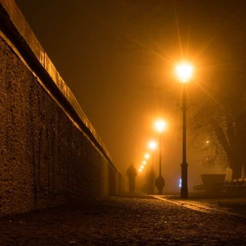 foggy night with street lamps on the sidewalk