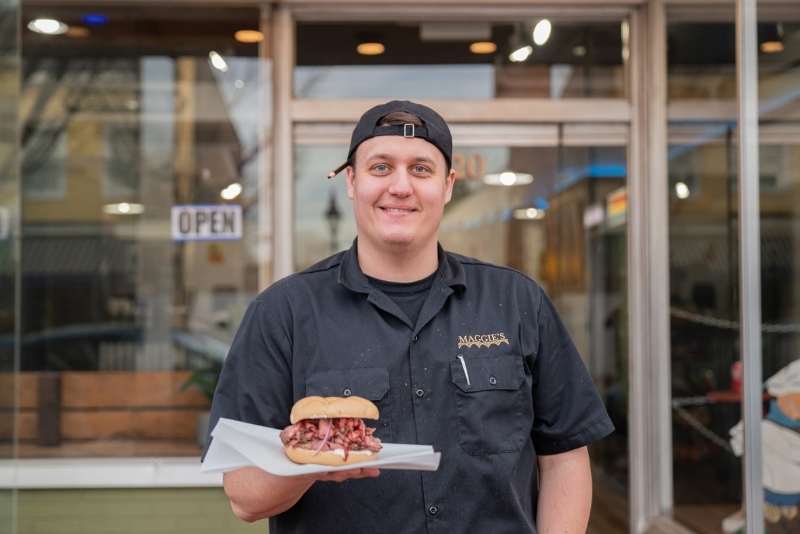 maggies owner holding sandwich outside restaurant