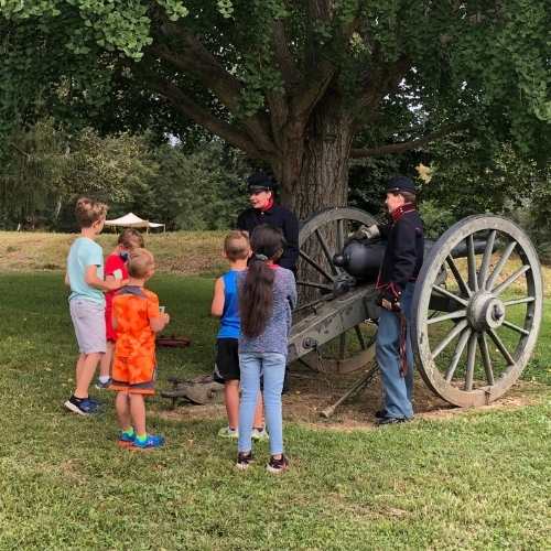 kids standing with civil war soldiers that are leaning on a cannon