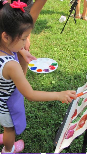 child painting on paper outside
