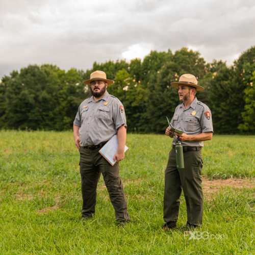 two national park service rangers standing in a field on the civil war battlefield