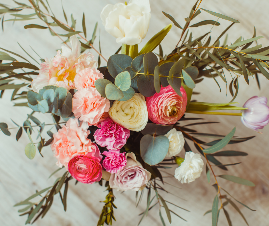 looking down at pink and peach roses and greenery in a vase