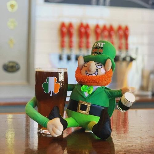 stuffed leprechaun with his arm around a pint of beer on the bar at Red Dragon Brewery. Beer taps in the background