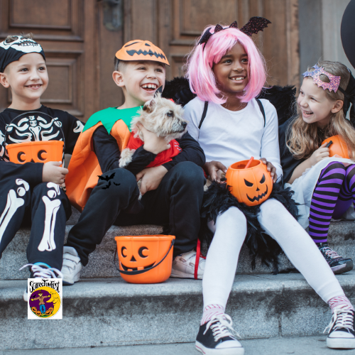 4 children in halloween costumes smiling and sitting on concrete steps