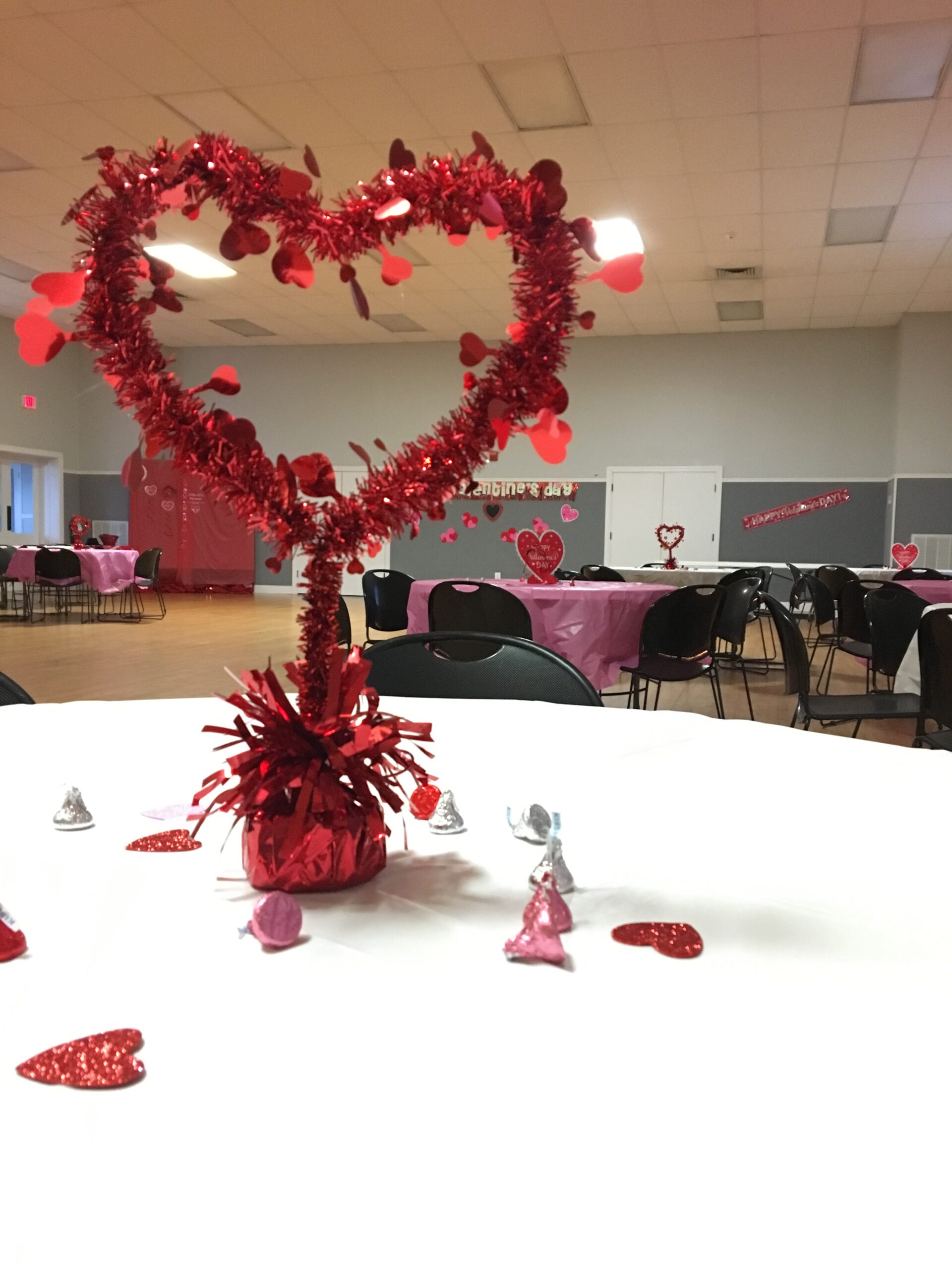 red heart garland in the shape of a heart in the middle of a table with a white tableclothe