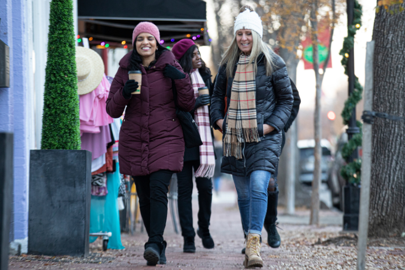 Four ladies walking down Caroline Street. Drinking coffee and talking