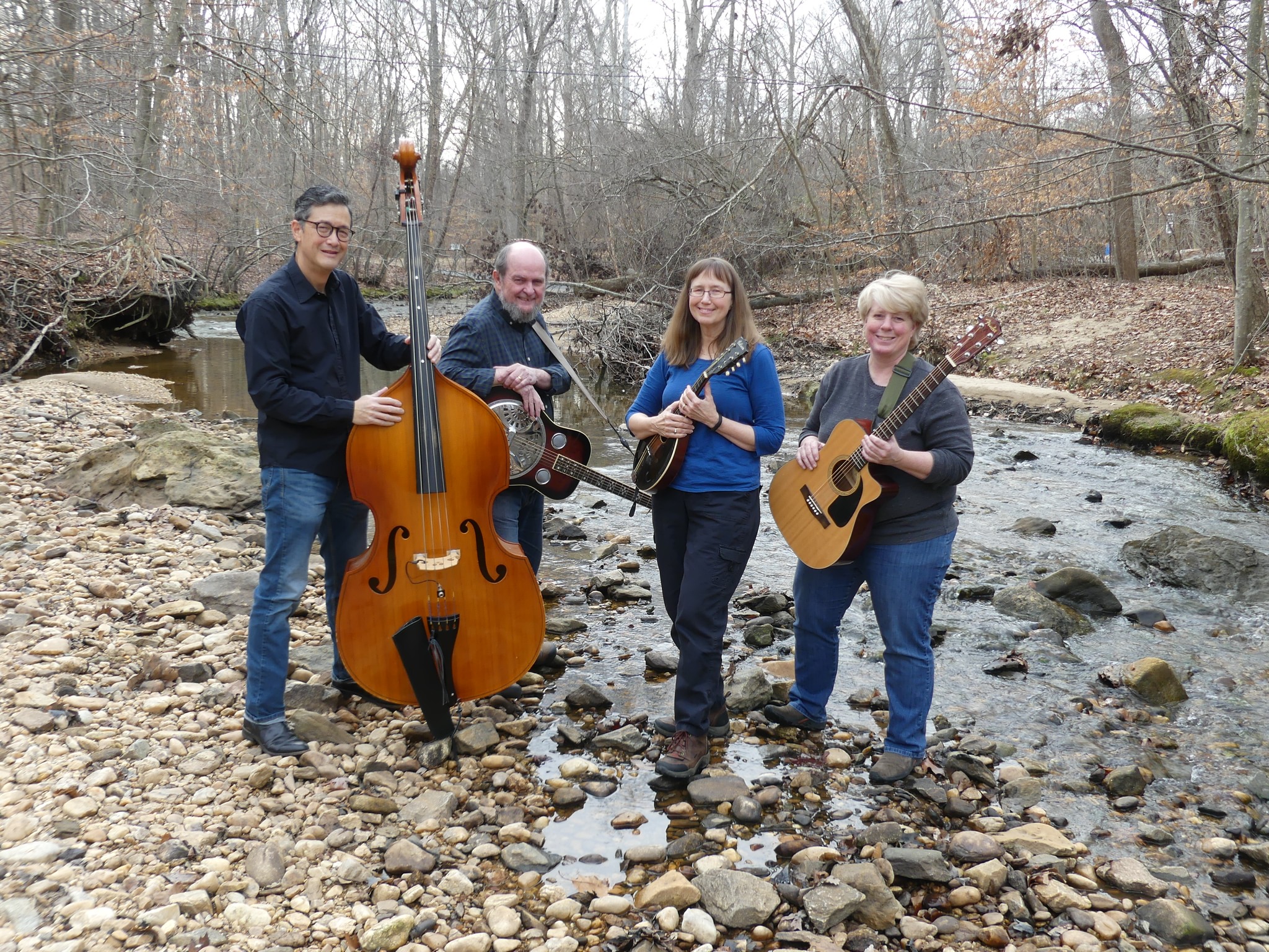 4 people with instruments by a creek