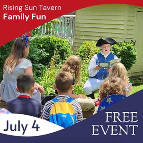 Man dressed from 1700s reading to kids in the yard of the Rising Sun Tavern