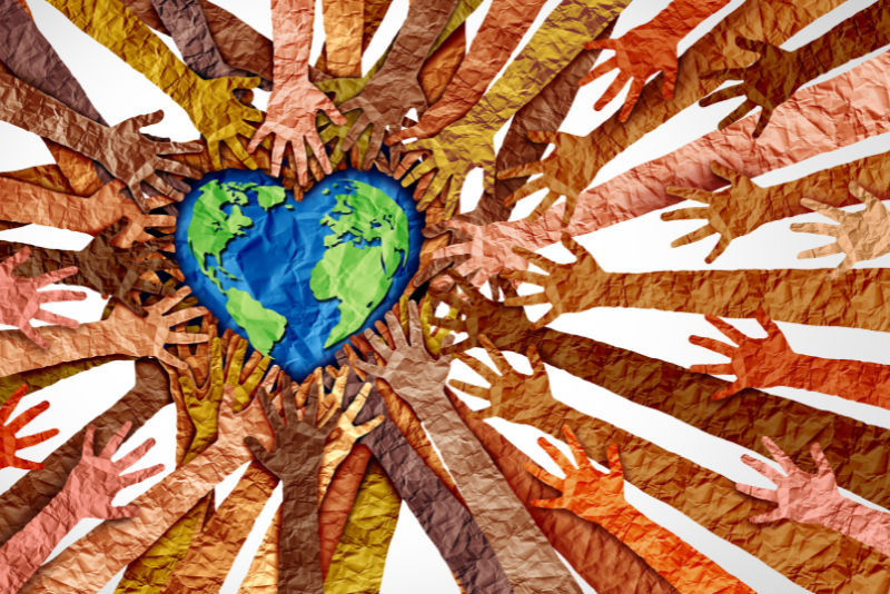 arms and hands reaching out to a heart-shaped earth. All the arms and the earth are made of crinkled paper. Arms are all earth-toned symbolizing diverse communities
