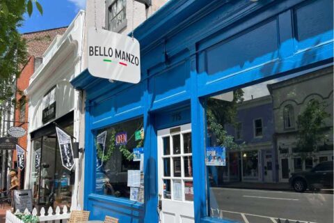 Blue downtown building with white sign that reads 'Bello Manzo,' tinted windows underneath