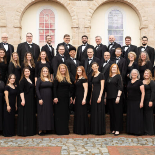 chamber chorale group standing on the steps at Market Square in Fredericksburg. 3 row of singers all dressed in black