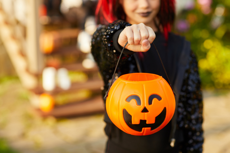 4 children in halloween costumes smiling and sitting on concrete steps