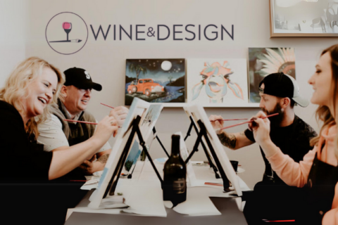 four people painting on easels n front of a wall with the wine and design logo