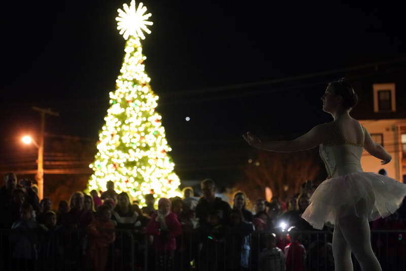 A person in a tutu dancing in front of a Christmas tree