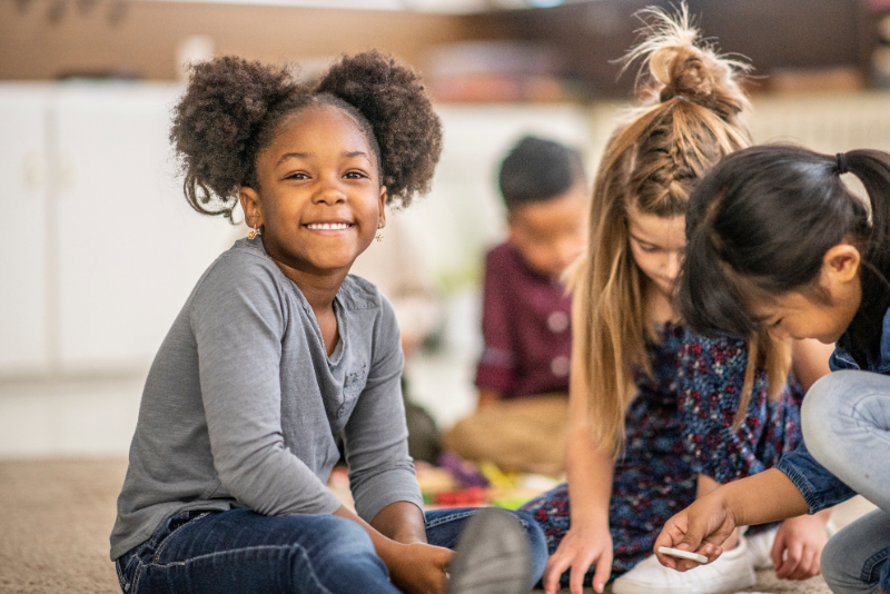 a group of children sitting on the floor in a classroom