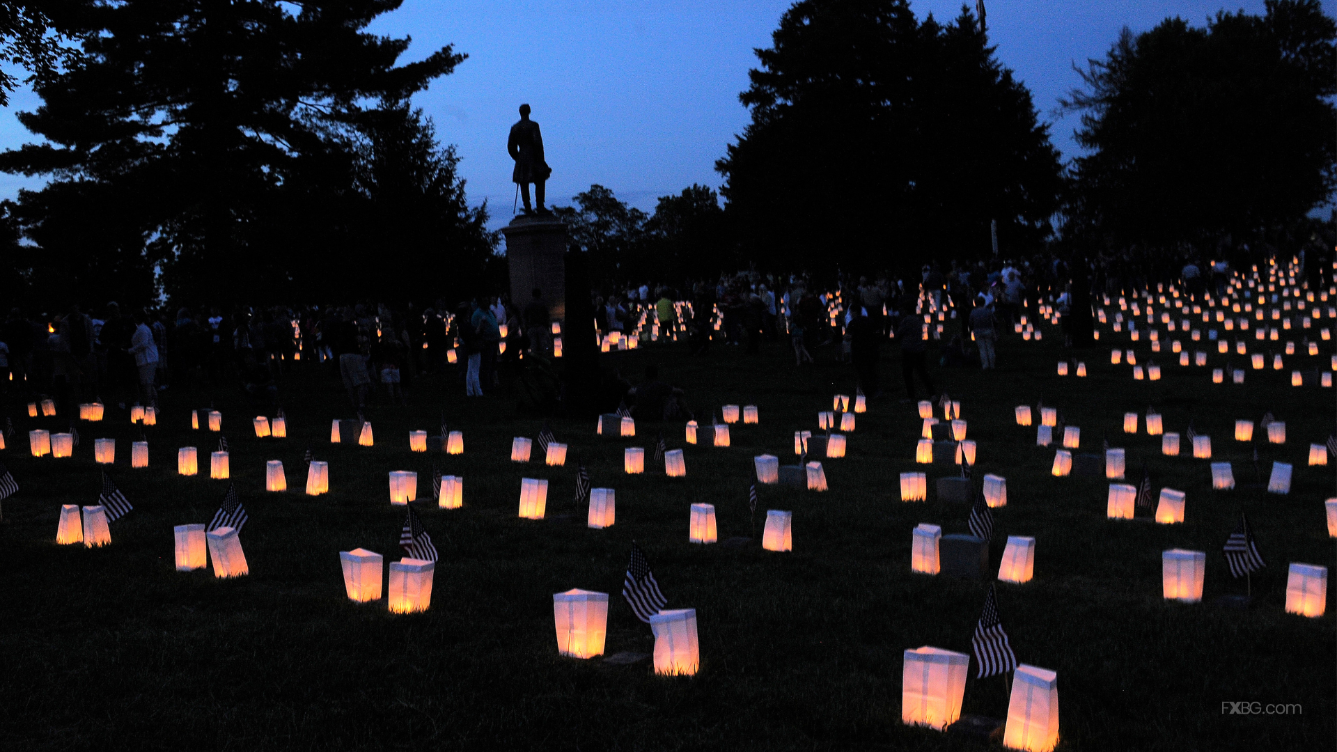 Hundreds of candle lit bags in the Fredericksburg National Cemetery at dusk. Civil War Statue in the background.