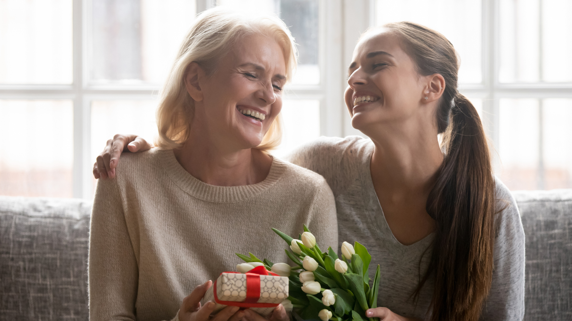 A mom and daughter exchanging gifts and smiling.