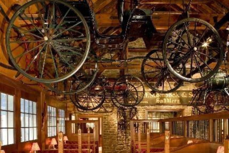 A restaurant housed in a historic carriage house with carriage wheels hanging from the ceiling. 