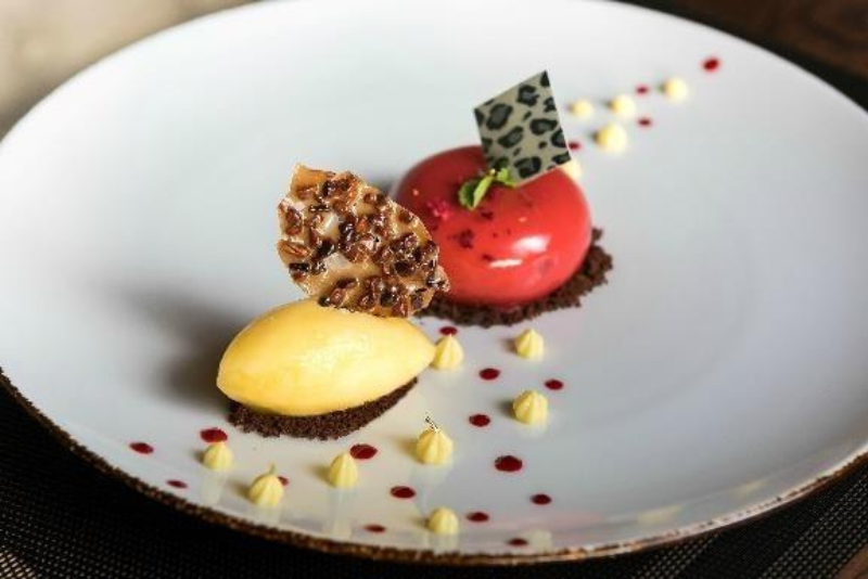Artisanal chocolates on a plate. One is yellow and one is red. 