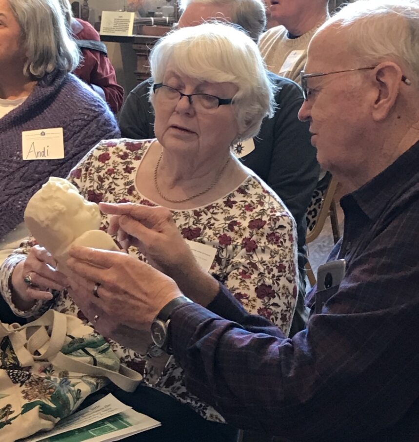 Two elderly people holding a piece of art.