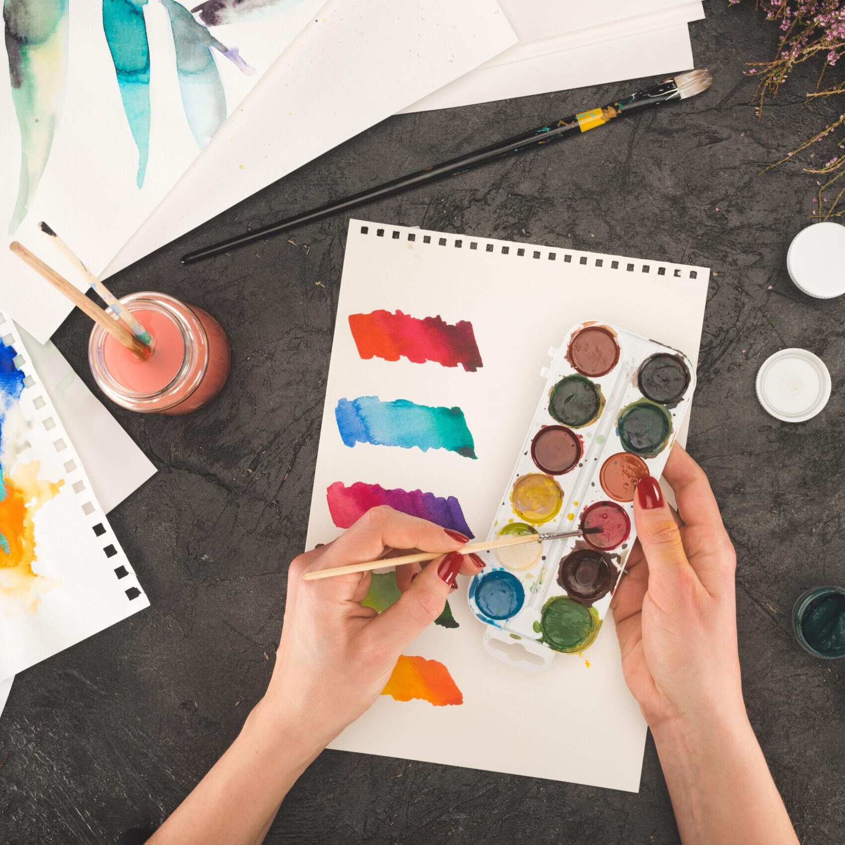 Two hands painting with watercolors.