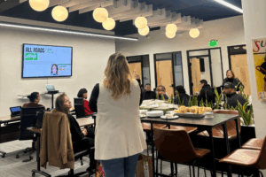 A speaker gives a presentation in front of a group in an office.