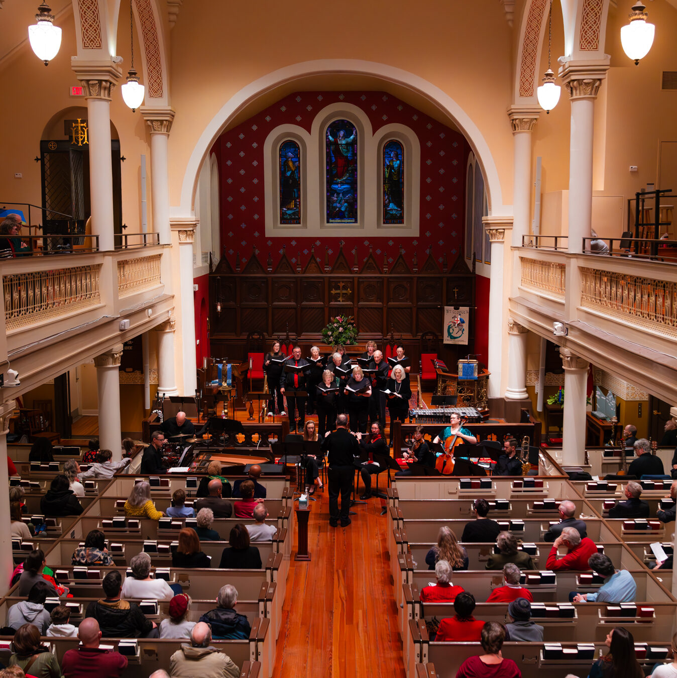 Christmas carolers performing in the worship hall of St. George's while people watch from pews.