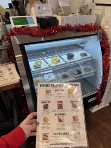 Hand holding a menu in front of a pastry case at Fearless cafe.