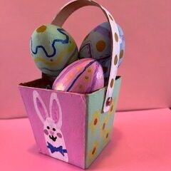 Paper mache easter basket filled with eggs on a pink background