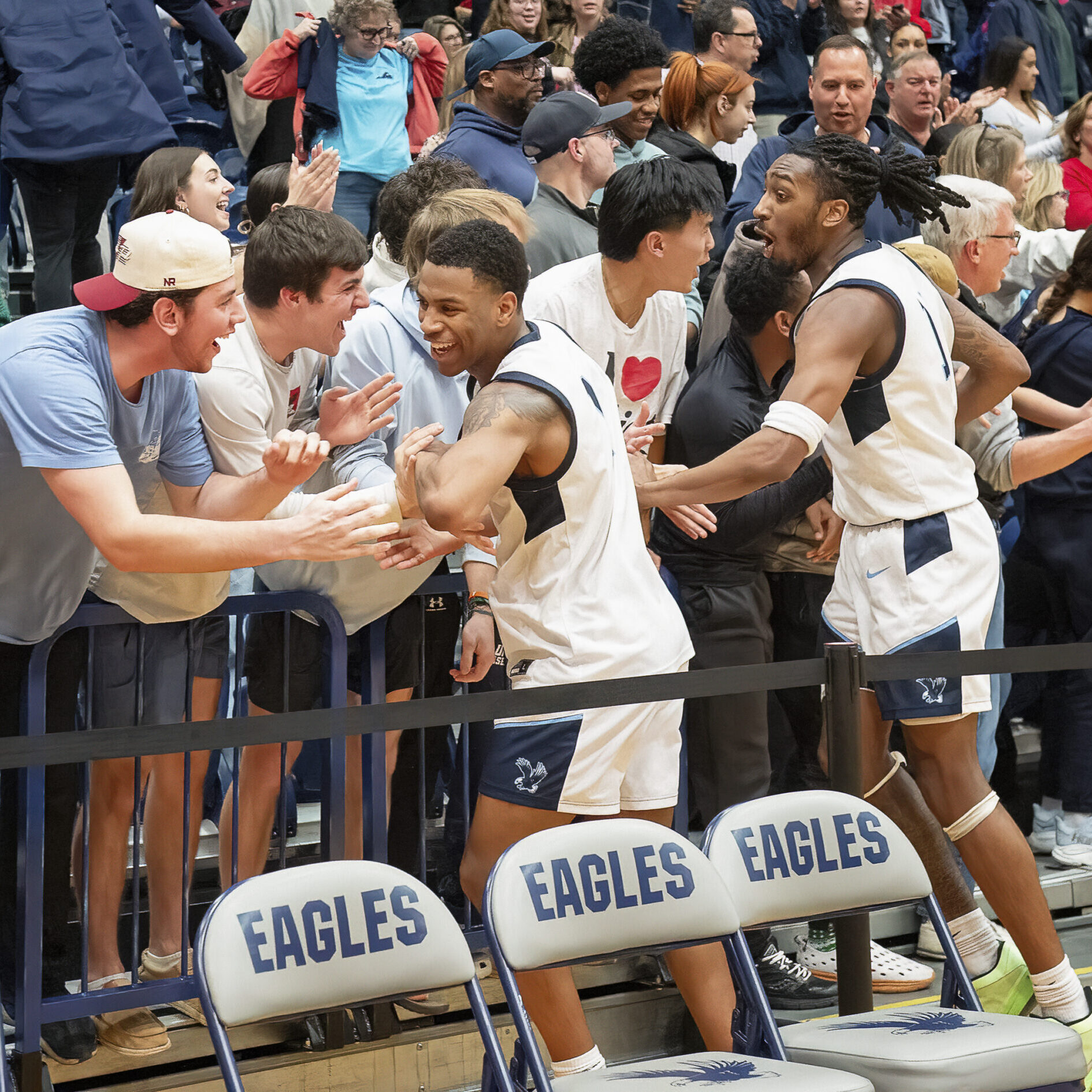 UMW Men's basketball players high fiving the crowd of fans during a game.